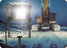 A large excavator on a snowy construction site at night. Long exposure with light painting.